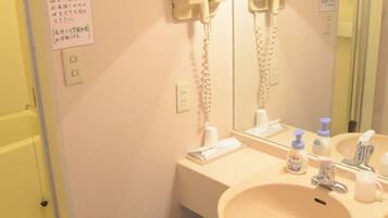 A bathroom with a sink, mirror, hairdryer, and a basket.
