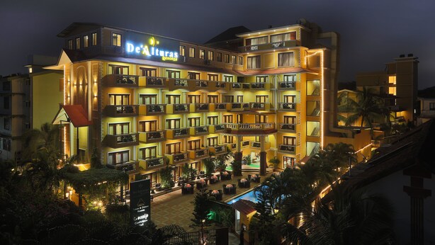 A multi-story hotel with balconies, a pool area, and a sign reading "De Alturas". - De Alturas Resort (Candolim)
