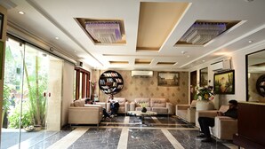A spacious lobby with a marble floor, a sofa set, a coffee table, and a bookshelf. - De Alturas Resort (Candolim)