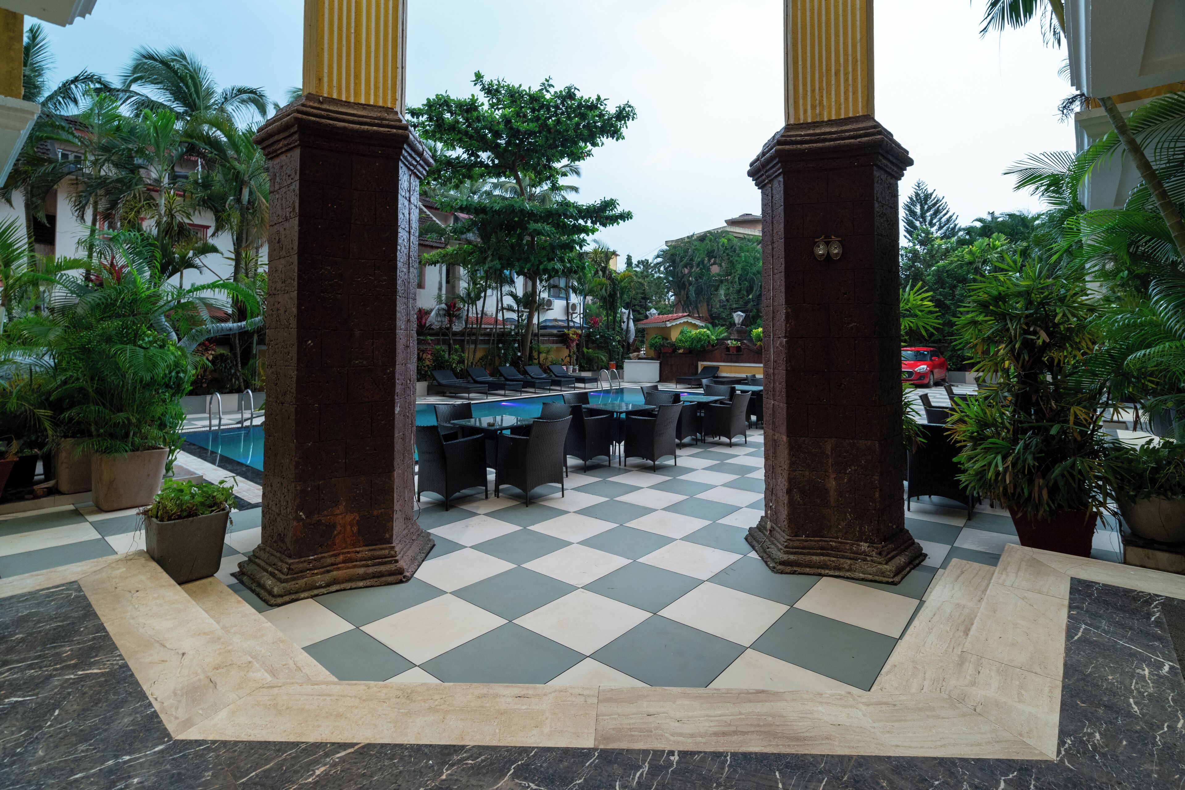 A checkered floor with a pool, outdoor seating, and palm trees.