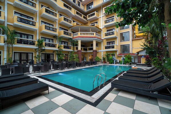 Ein Hotelpoolbereich mit Liegestühlen und einem Schwimmbecken.
