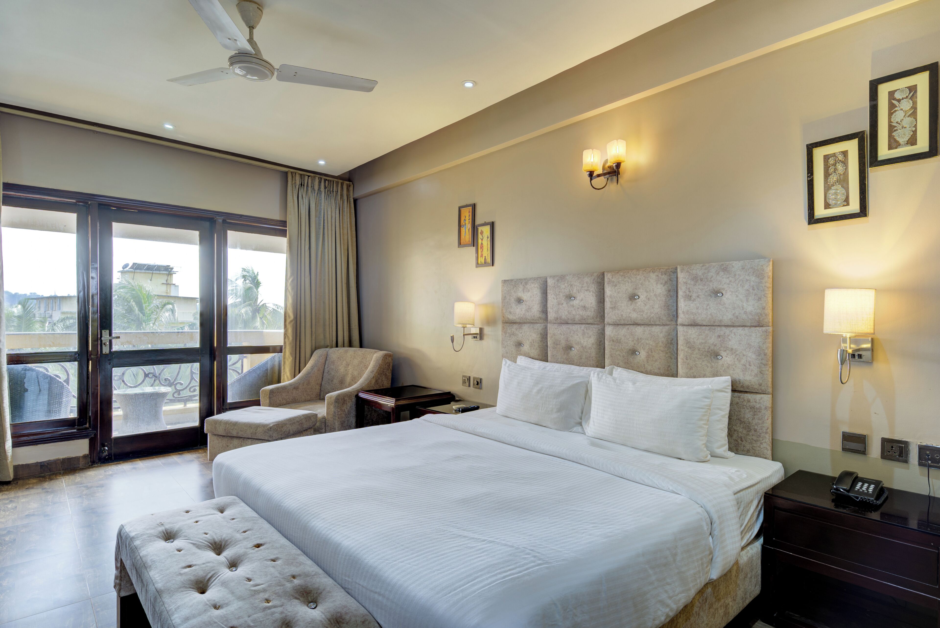 Hotelkamer met een groot bed, een stoel, een bureau en een balkon met uitzicht.