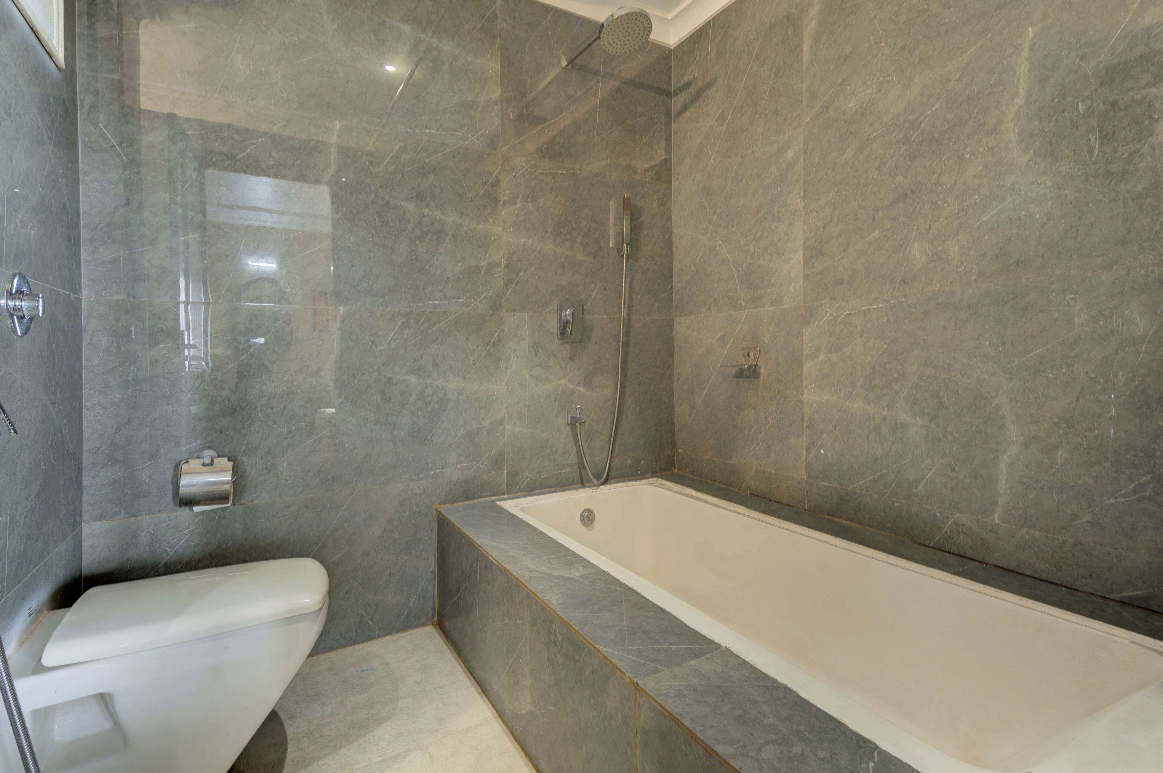 A modern bathroom with a bathtub, toilet, and shower.