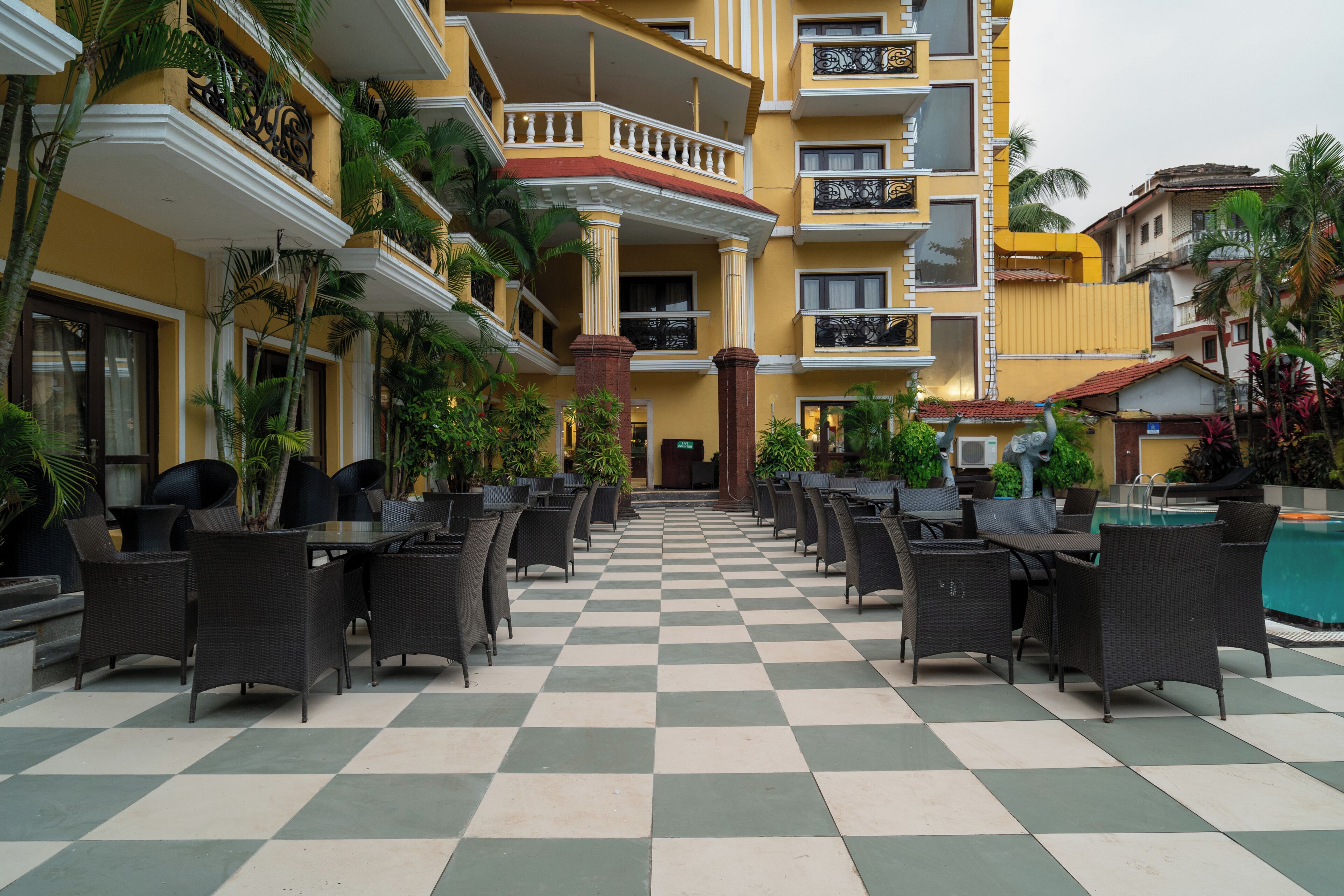 A hotel courtyard with checkered flooring, outdoor seating, and a pool.