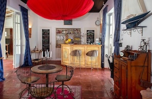 A cozy room with a wooden cabinet, a round table with chairs, a bookshelf, and a red curtain. - Pousada Casa Nova Buzios (Buzios)