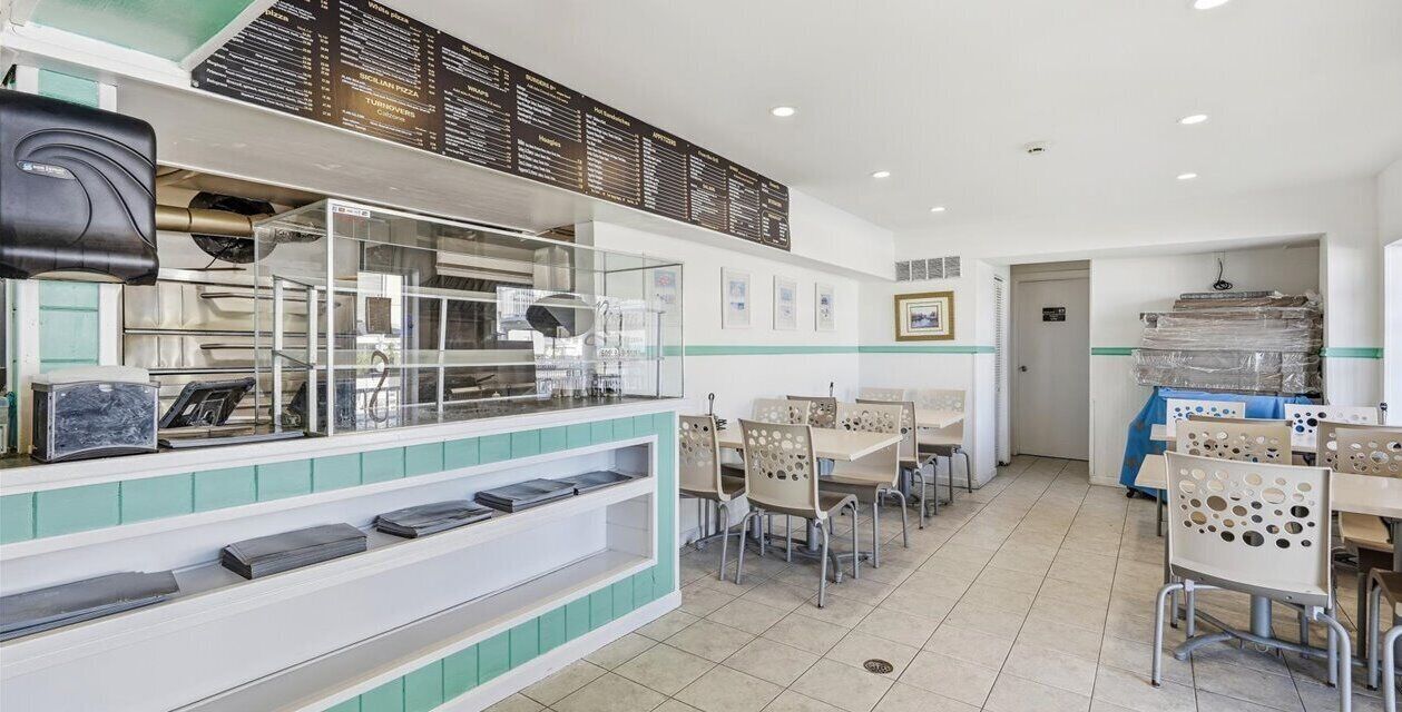 Un restaurant avec un comptoir, des chaises et un tableau affichant le menu.