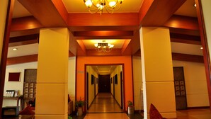 Ein Hotelgang mit einer Chandelüster, Holzbalken und einem Schild, das den Ausgang weist.