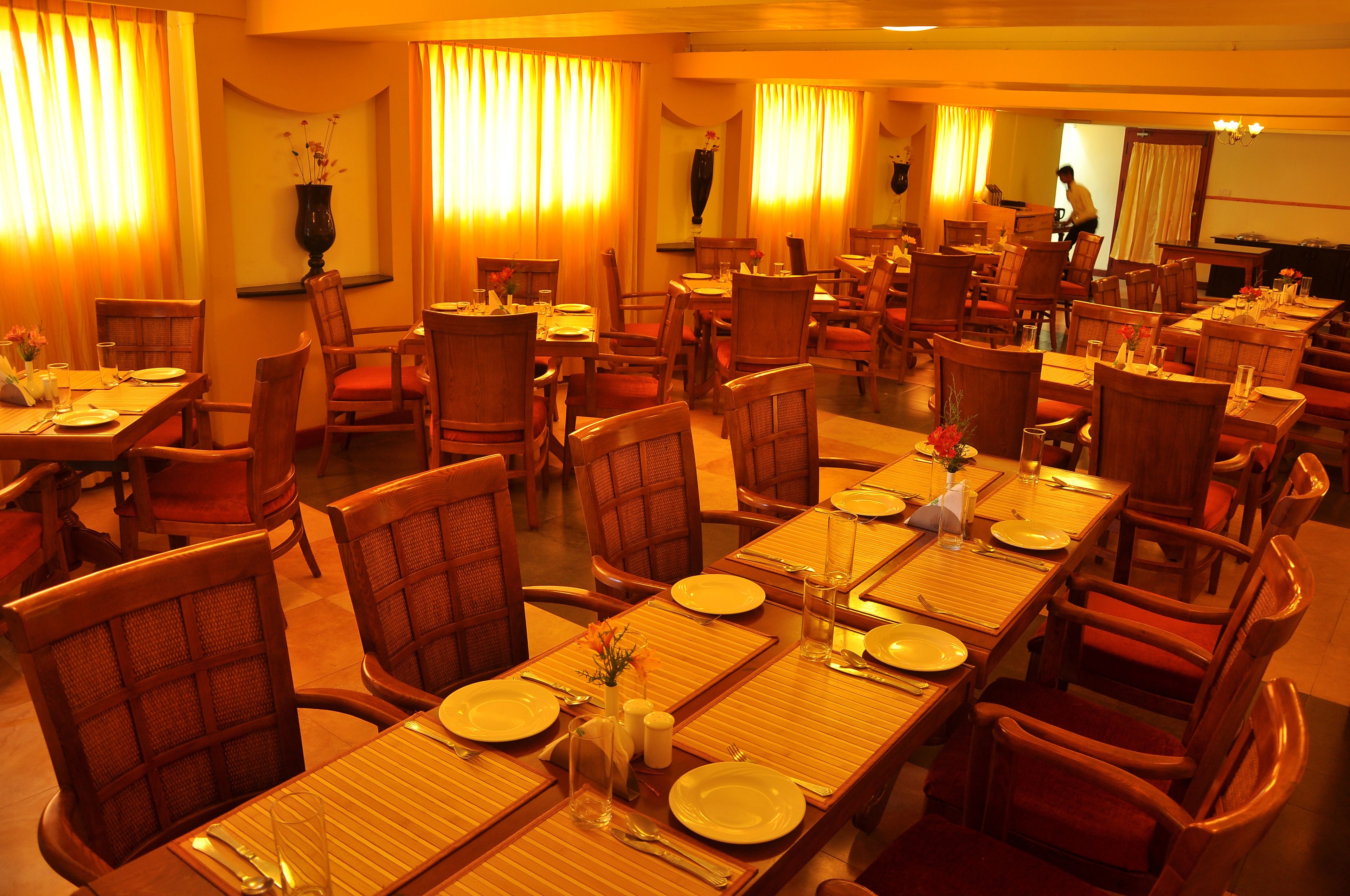 Un restaurant doté de nombreuses tables et chaises, chacune étant mise avec des assiettes, des couverts et des verres.