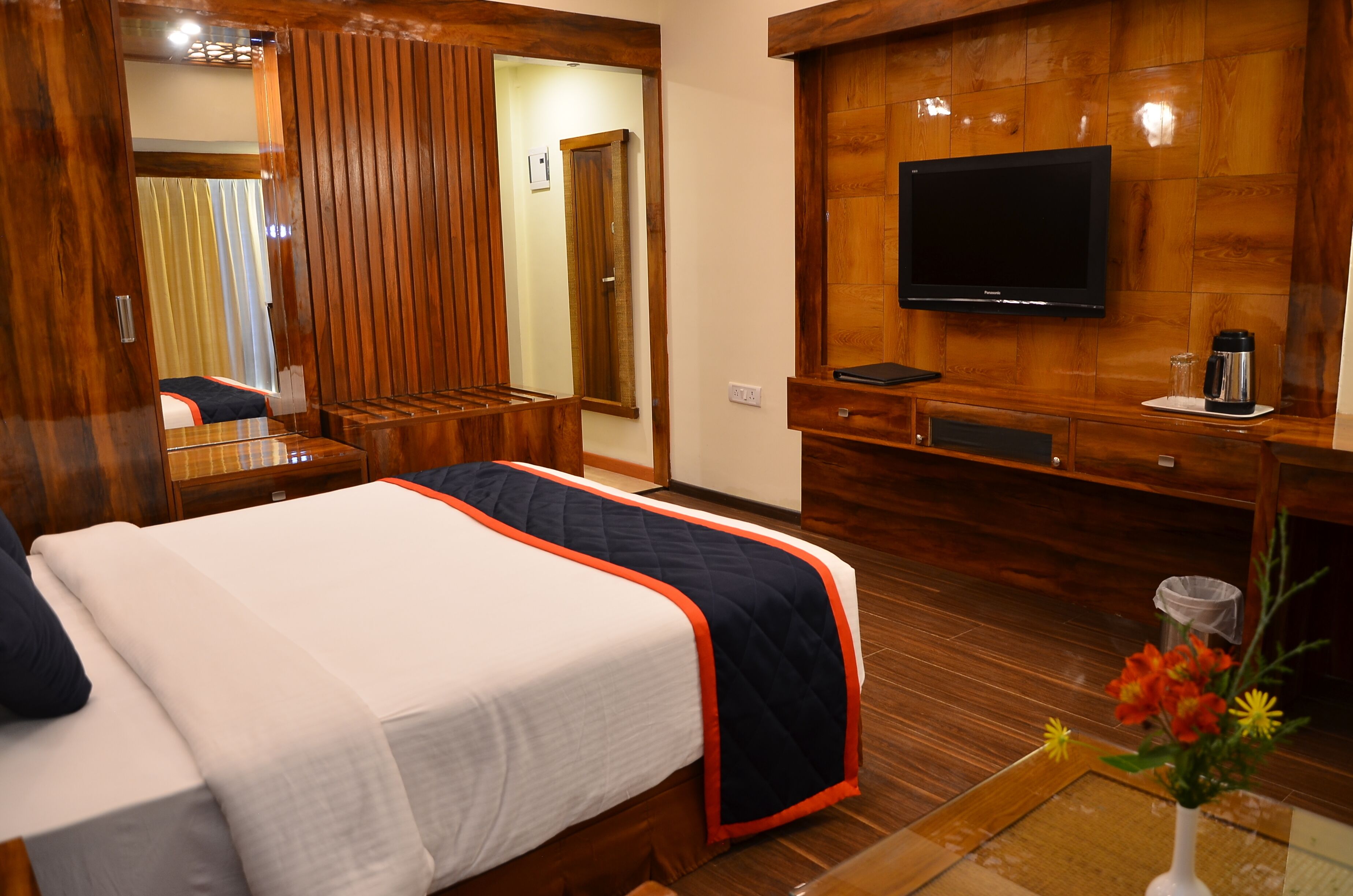 A hotel room with two beds, a TV, wooden paneling, and a small table with a coffee maker.