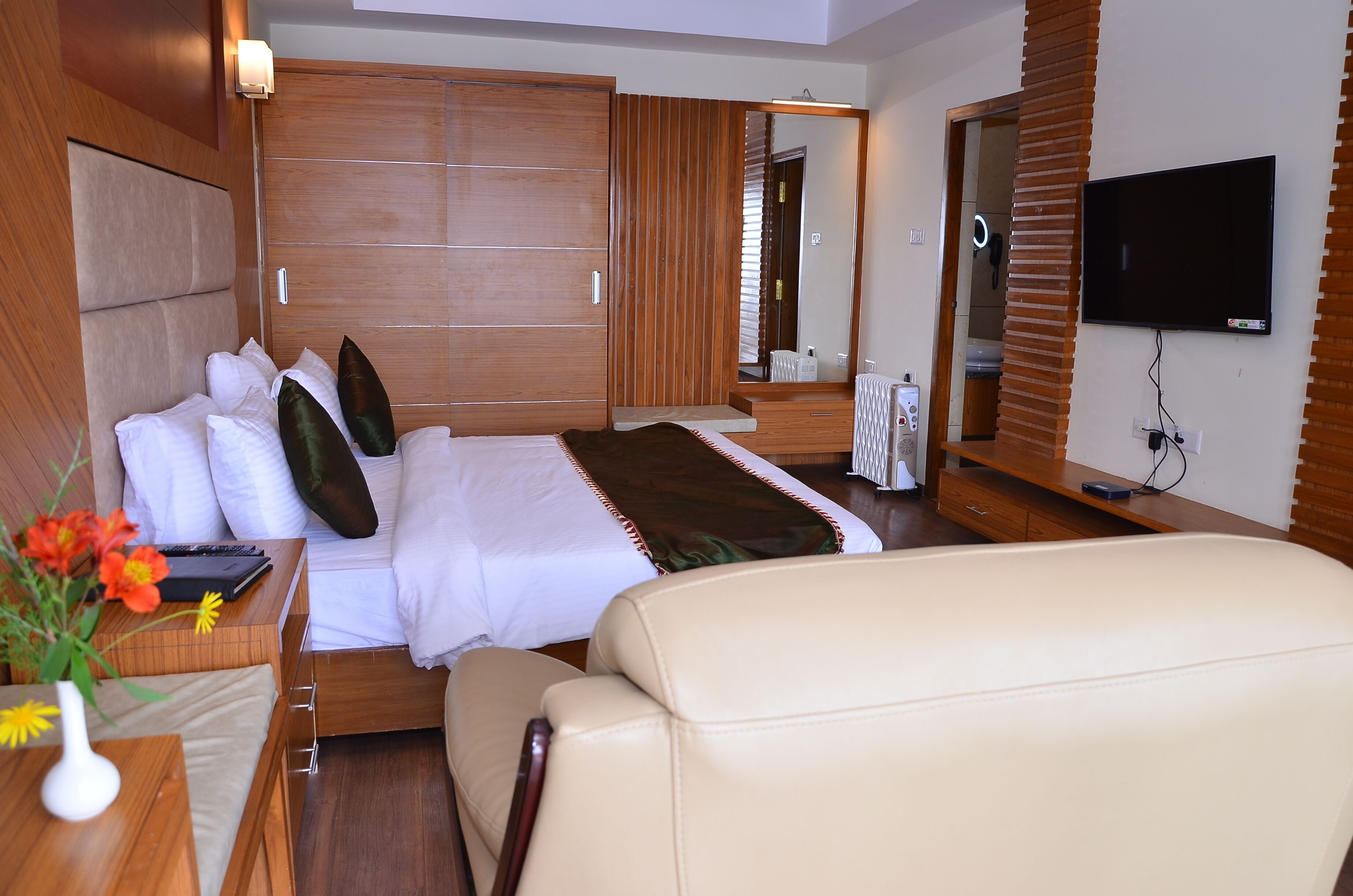 Une chambre d’hôtel moderne avec un grand lit, une télévision et une armoire en bois.
