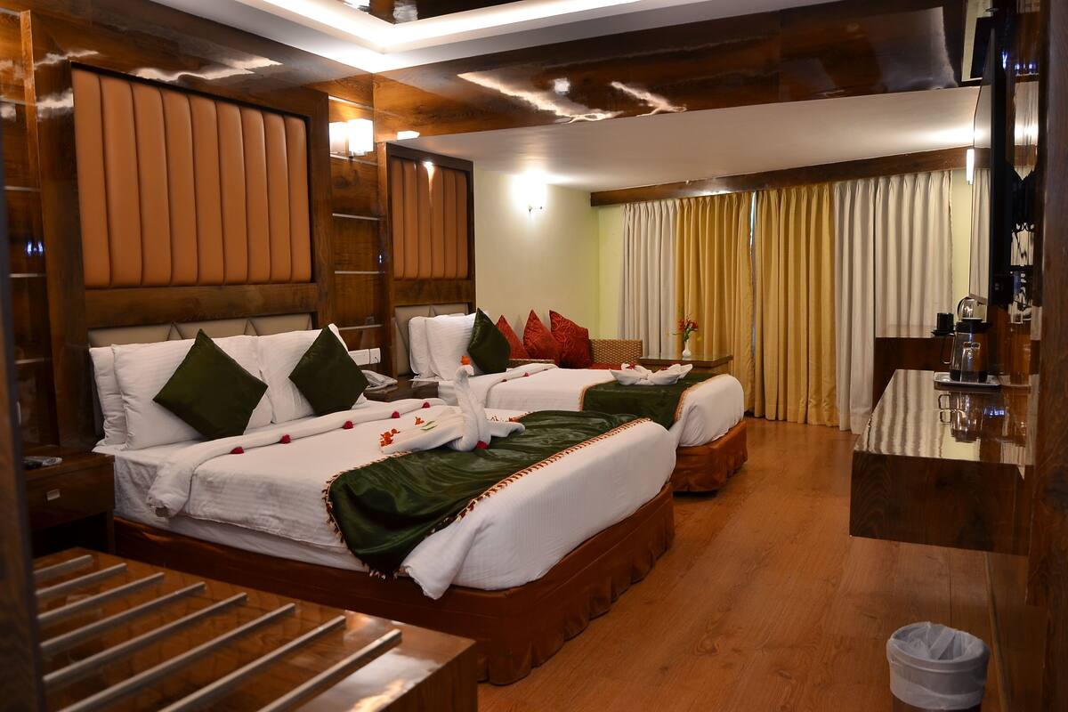 Una habitación de hotel con dos camas, cabeceros de madera, una mesita y un espejo.
