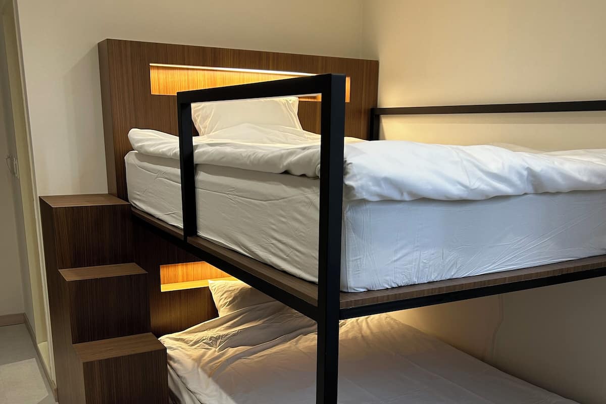 Una cama litera con cabecera de madera y escalones integrados.