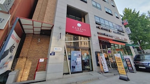 A multi-story building with a Hostel Korea sign, a 7-Eleven store, and various other businesses. - Bound Hostel (Seoul)