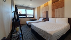 A hotel room with two beds, a desk, a chair, and a window with a view of buildings. - Bound Hostel (Seoul)