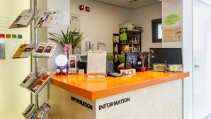 A reception desk with a clock, informational brochures, and a plant. - Bound Hostel (Seoul)