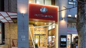 A Hostel Korea building with a modern design, featuring a prominent red sign and a glass entrance.