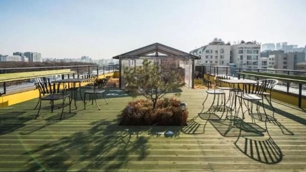 A rooftop terrace with outdoor seating, a small garden, and a view of the city skyline. - Bound Hostel (Seoul)