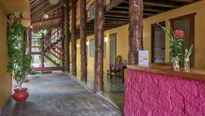 A hotel lobby with a wooden staircase, a reception desk, and a large potted plant. - Koox City Garden Hotel (Playa del Carmen)