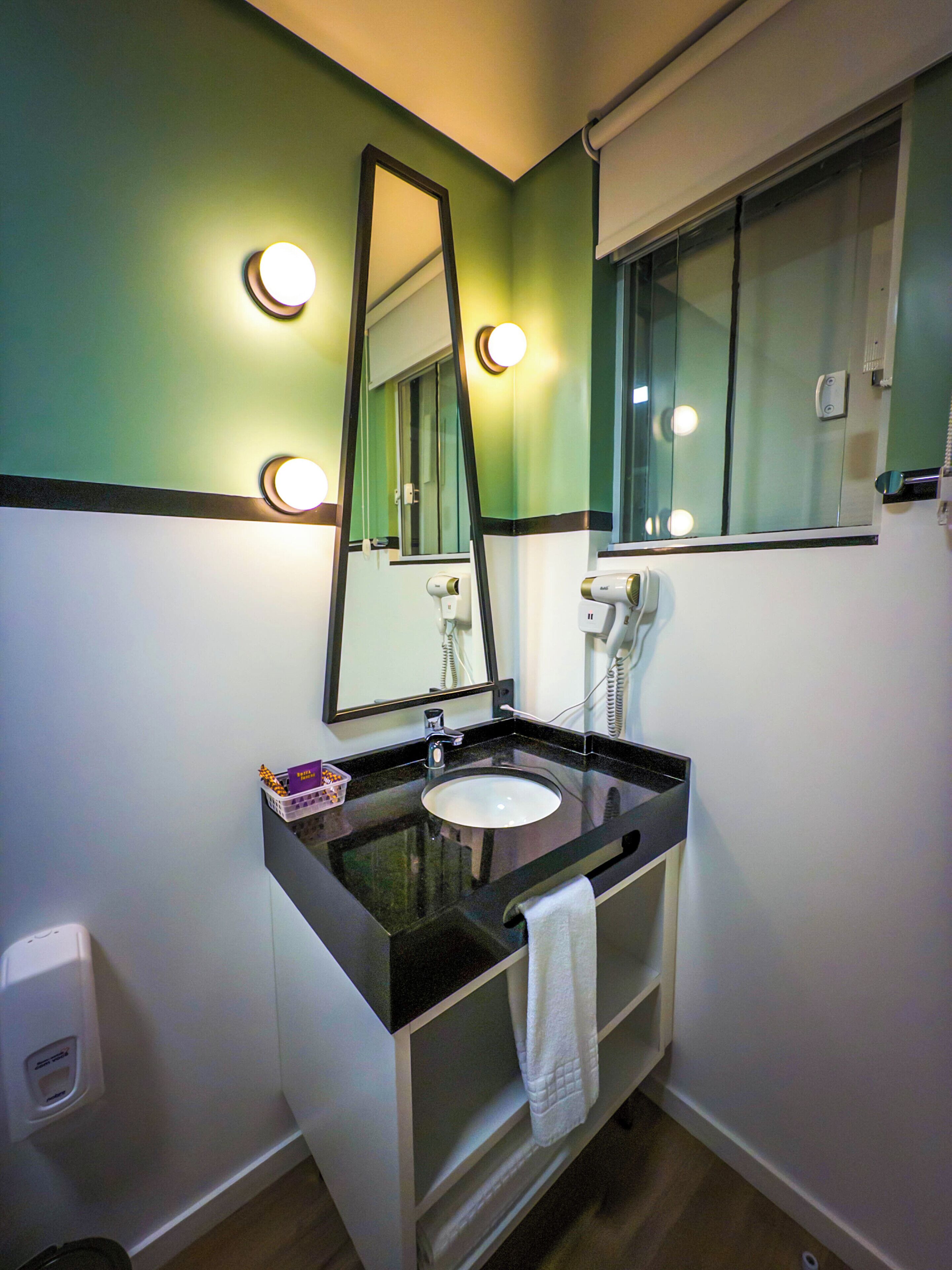 A bathroom with a sink, mirror, and hairdryer.