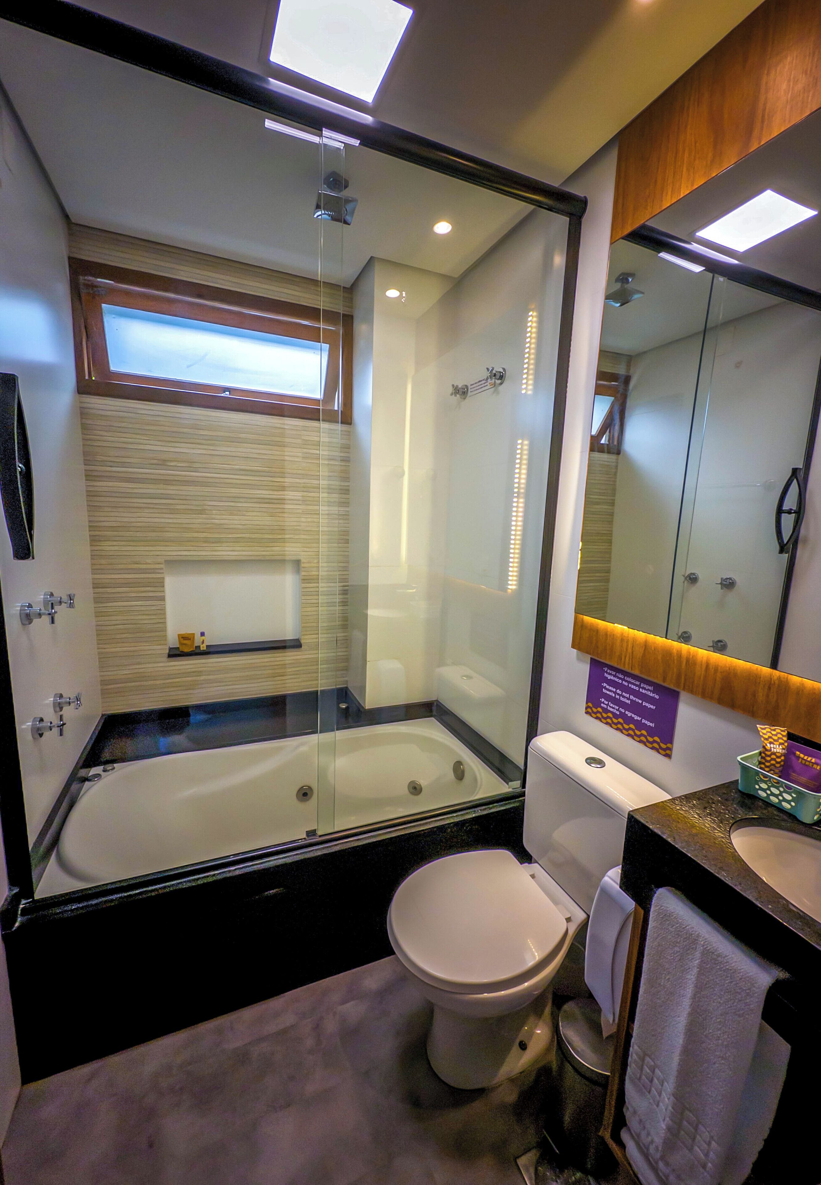 A modern bathroom with a glass-enclosed shower, a separate toilet, and a vanity with a mirror.