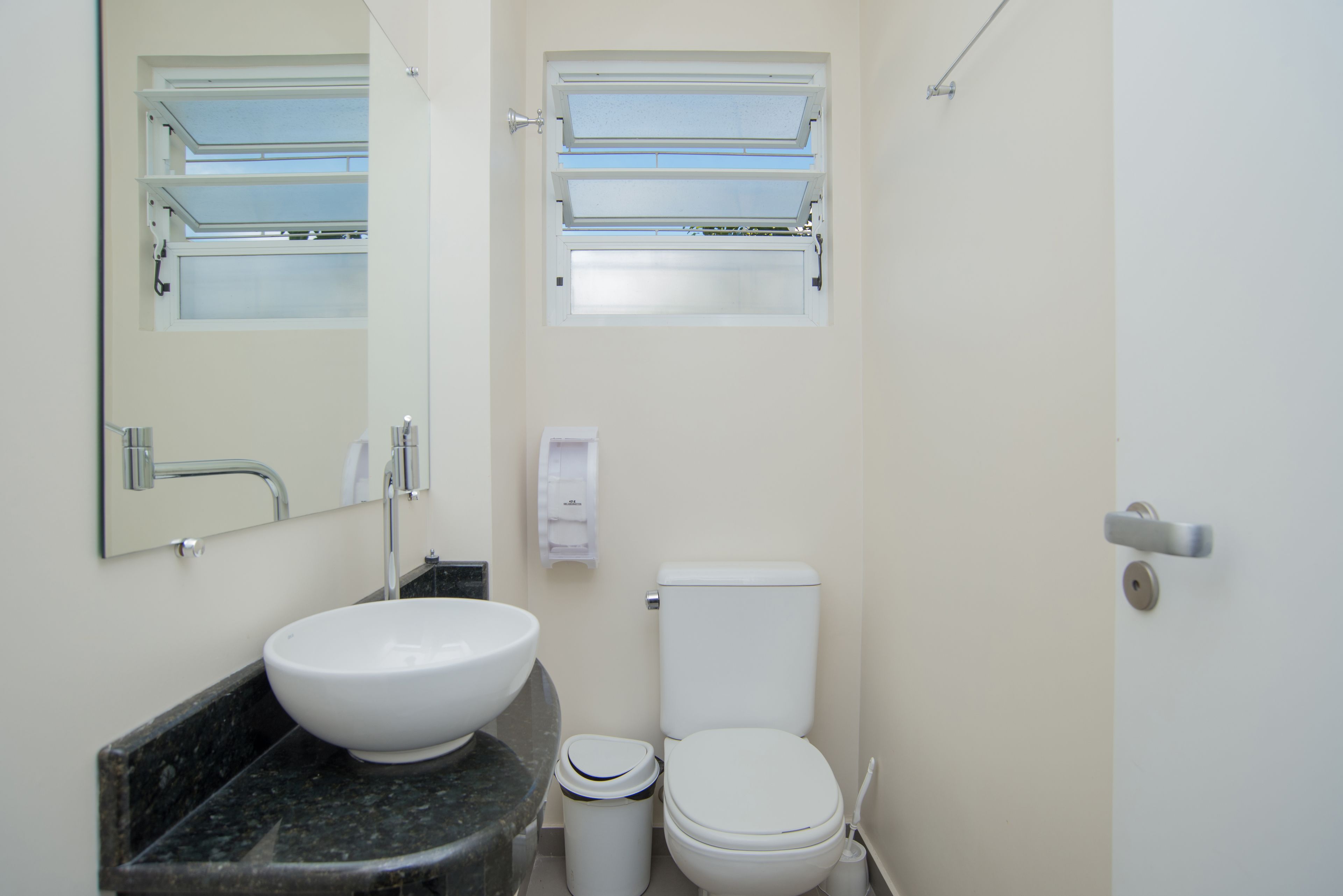 A bathroom with a white sink, toilet, and a mirror above the sink.