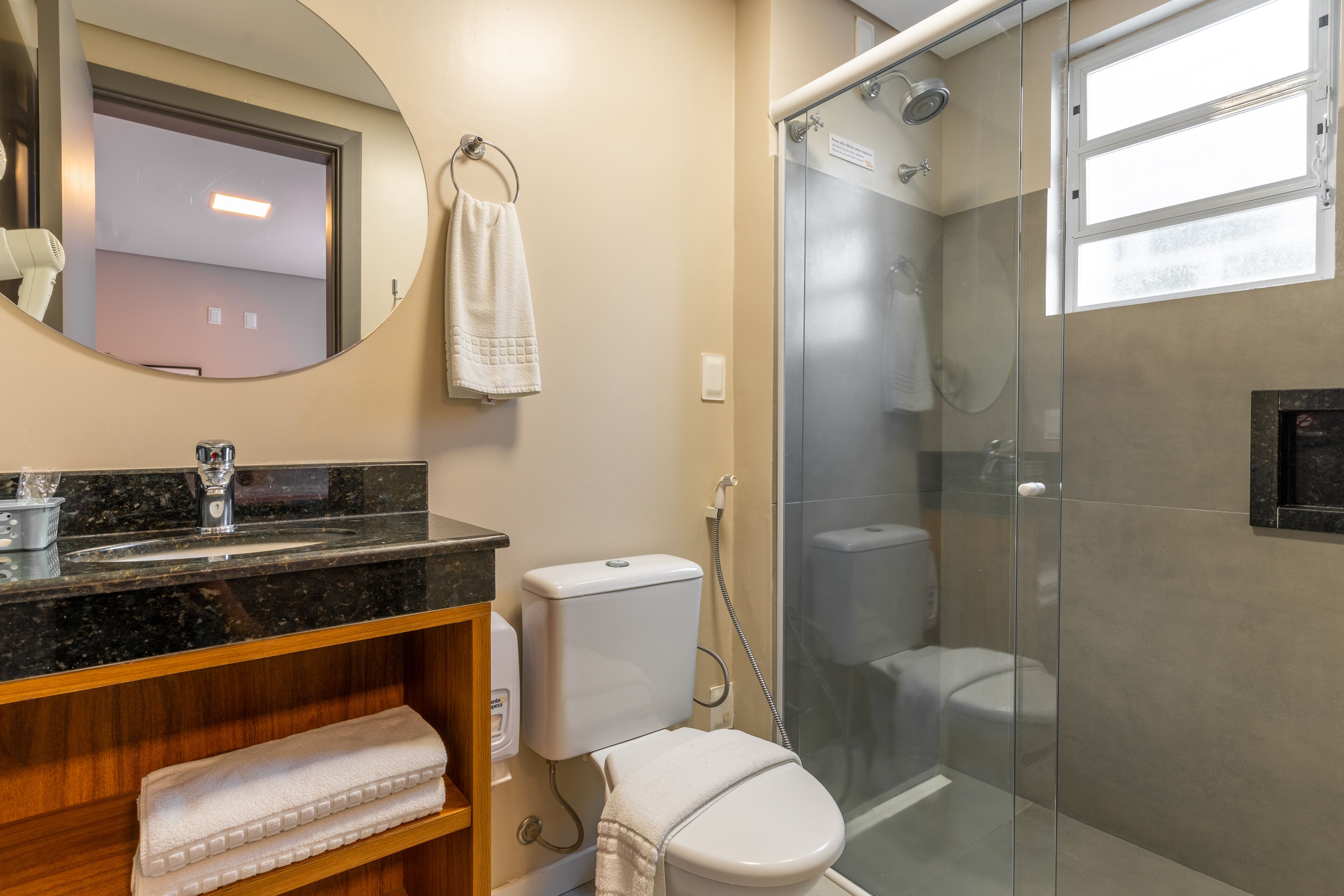 Un baño moderno con ducha de vidrio, encimera de mármol y retrete.