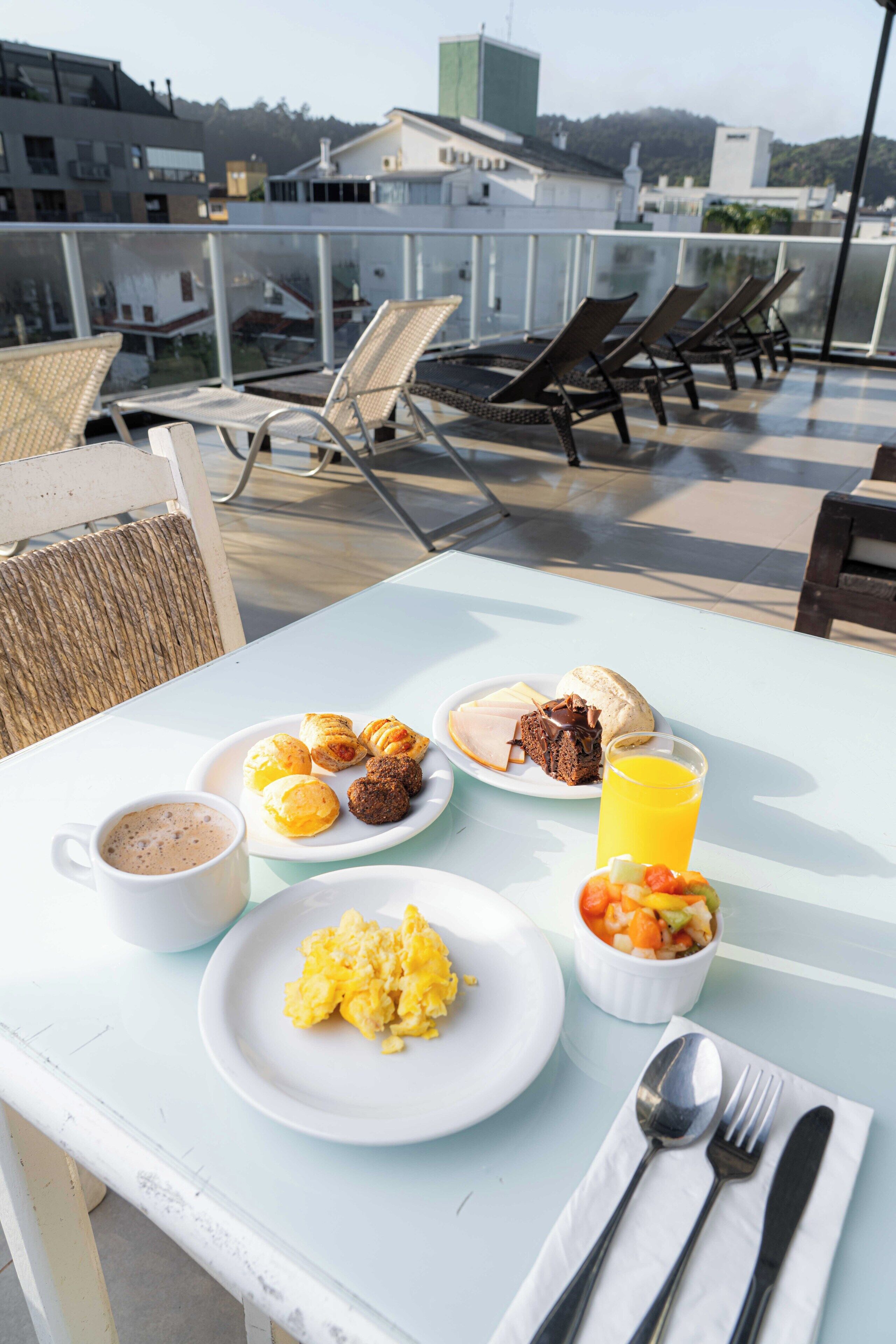A table with breakfast items including eggs, croissants, and a muffin, along with a cup of coffee and a glass of orange juice.