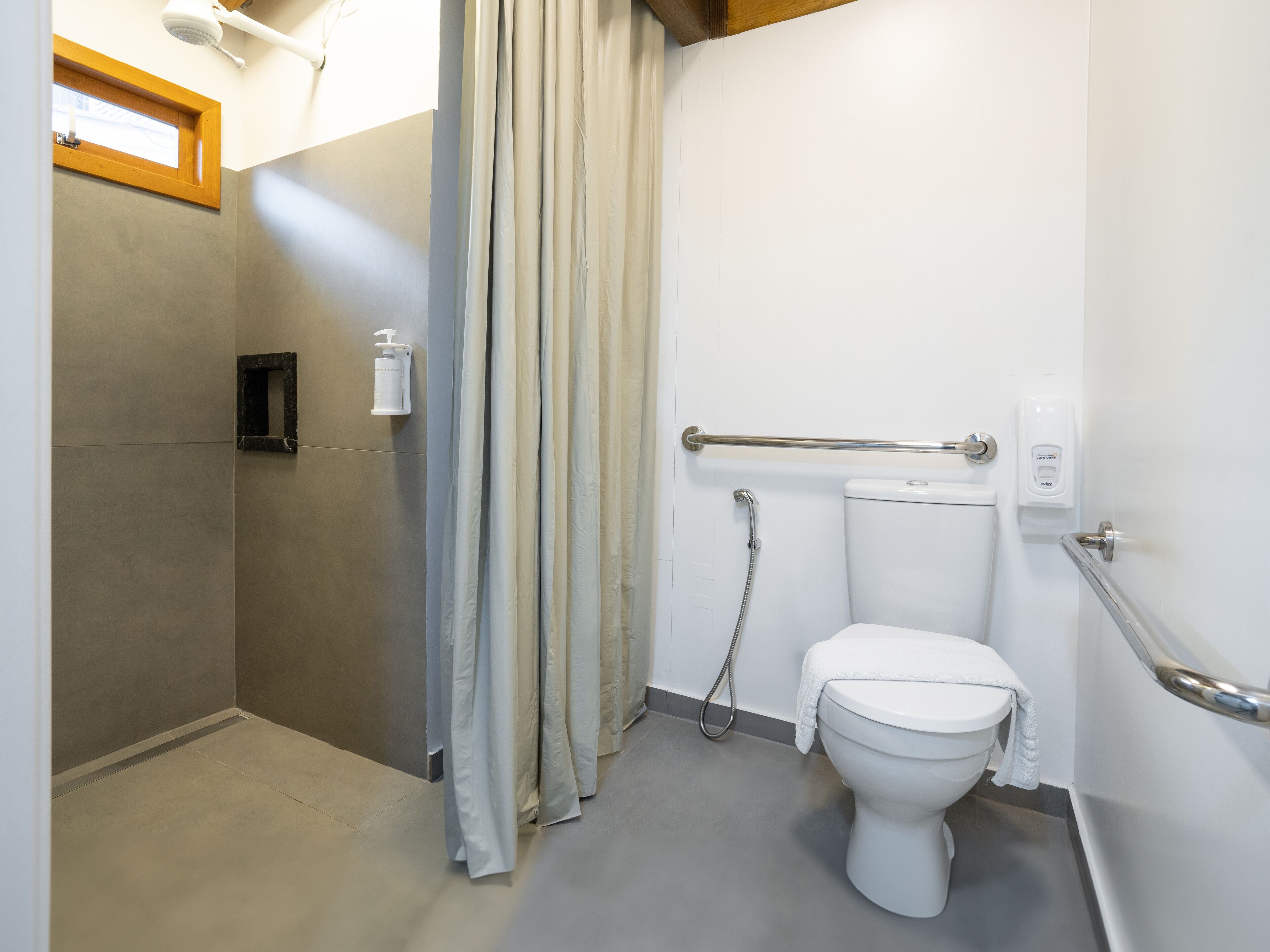 A modern bathroom with a shower, toilet, and a hand sanitizer dispenser.