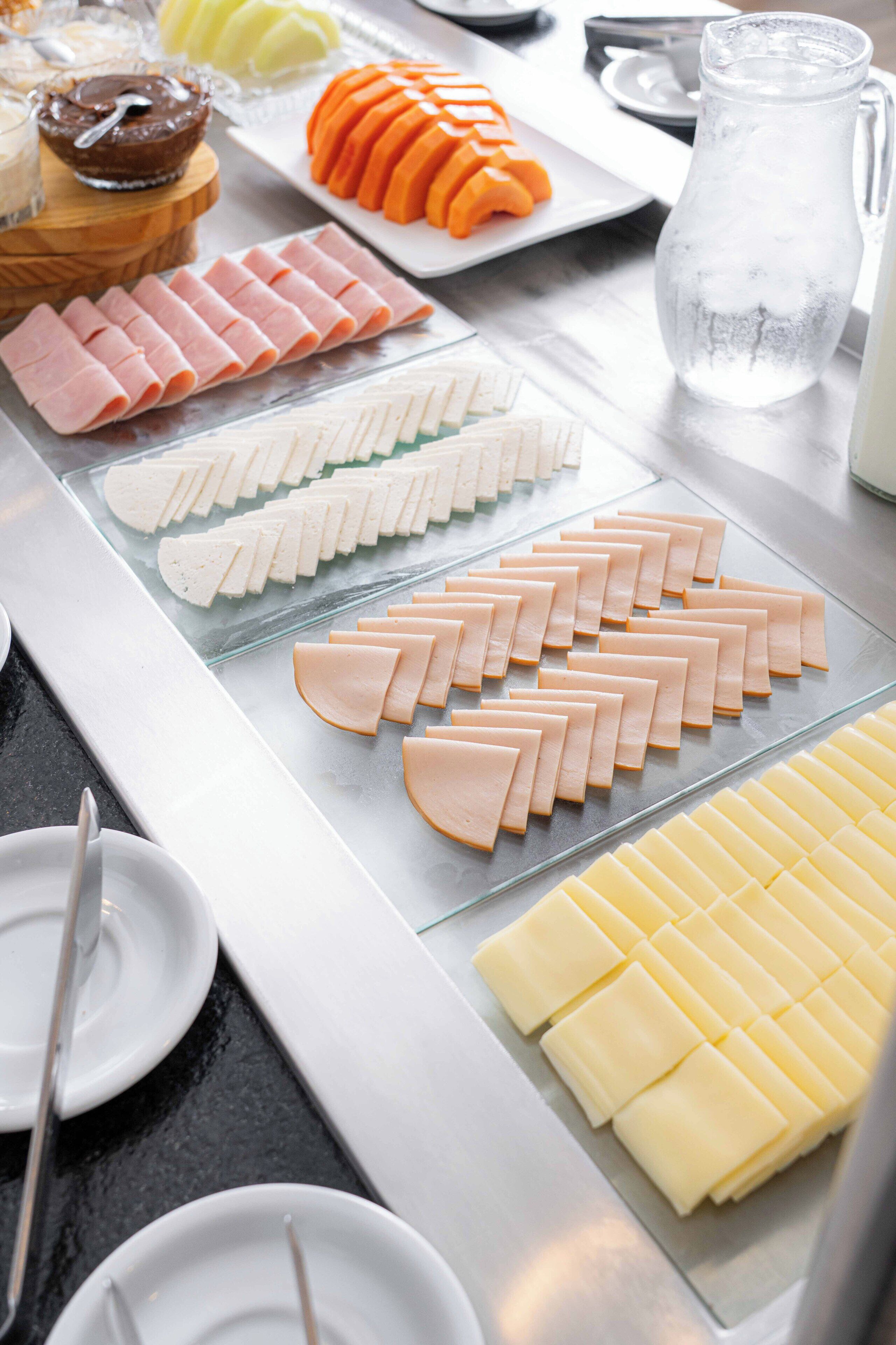 Ein Buffet mit verschiedenen Speisen, darunter Aufschnitt, Käse und Obst.