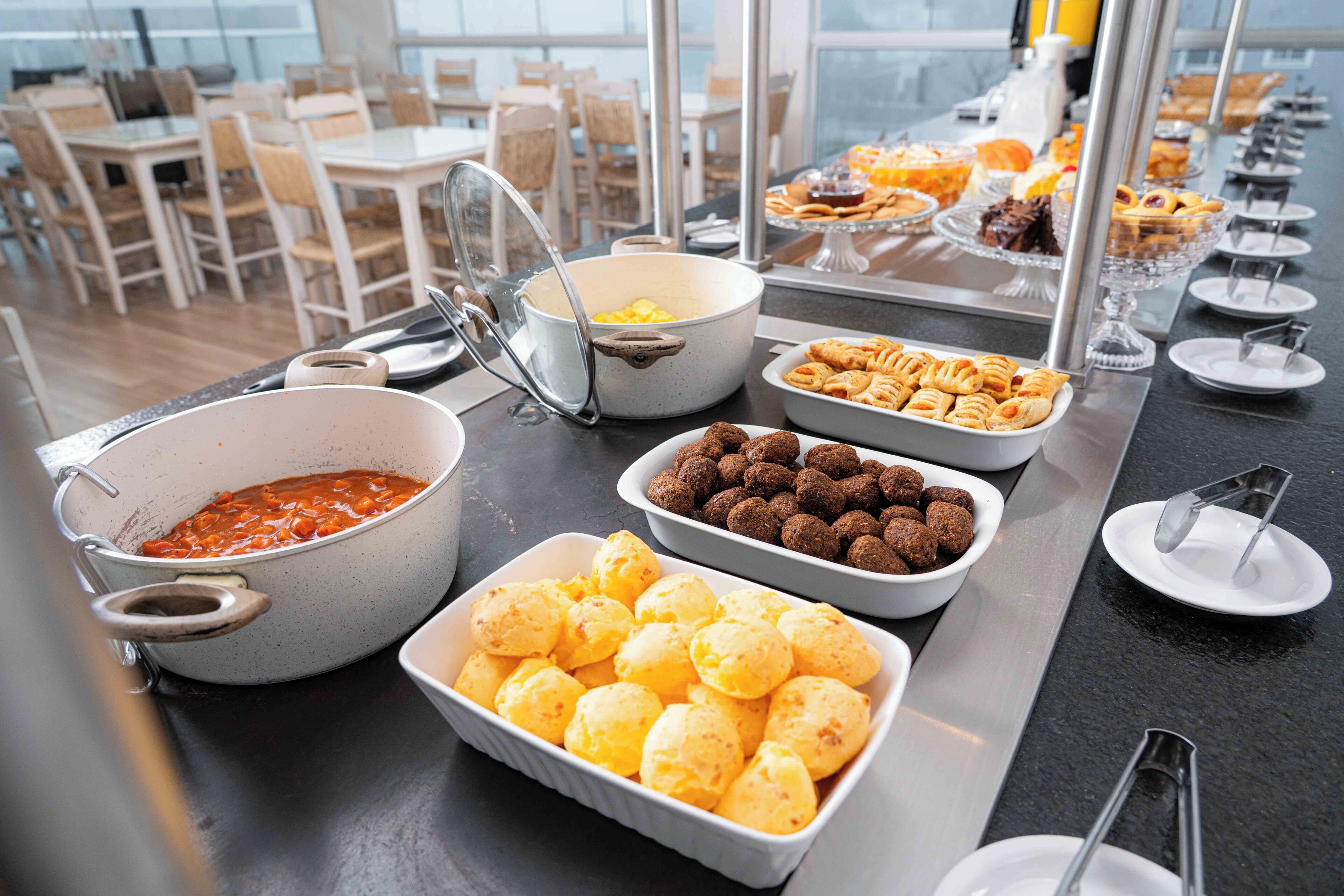 Ein Buffet mit verschiedenen Speisen, darunter eine Suppenterrine, eine Schale mit Brötchen und eine Auswahl an Gebäck.