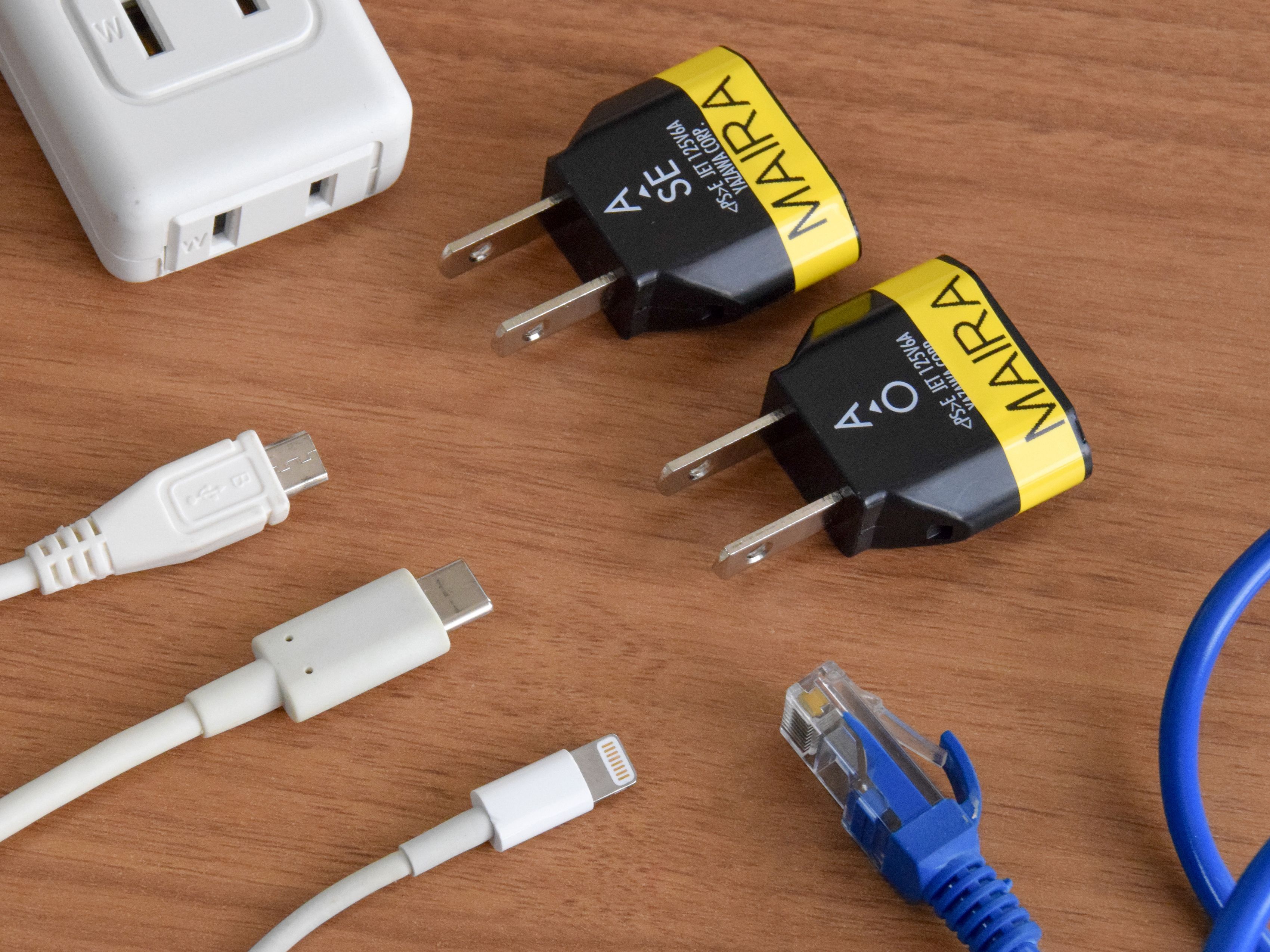Two power adapters and a USB cable on a wooden surface.