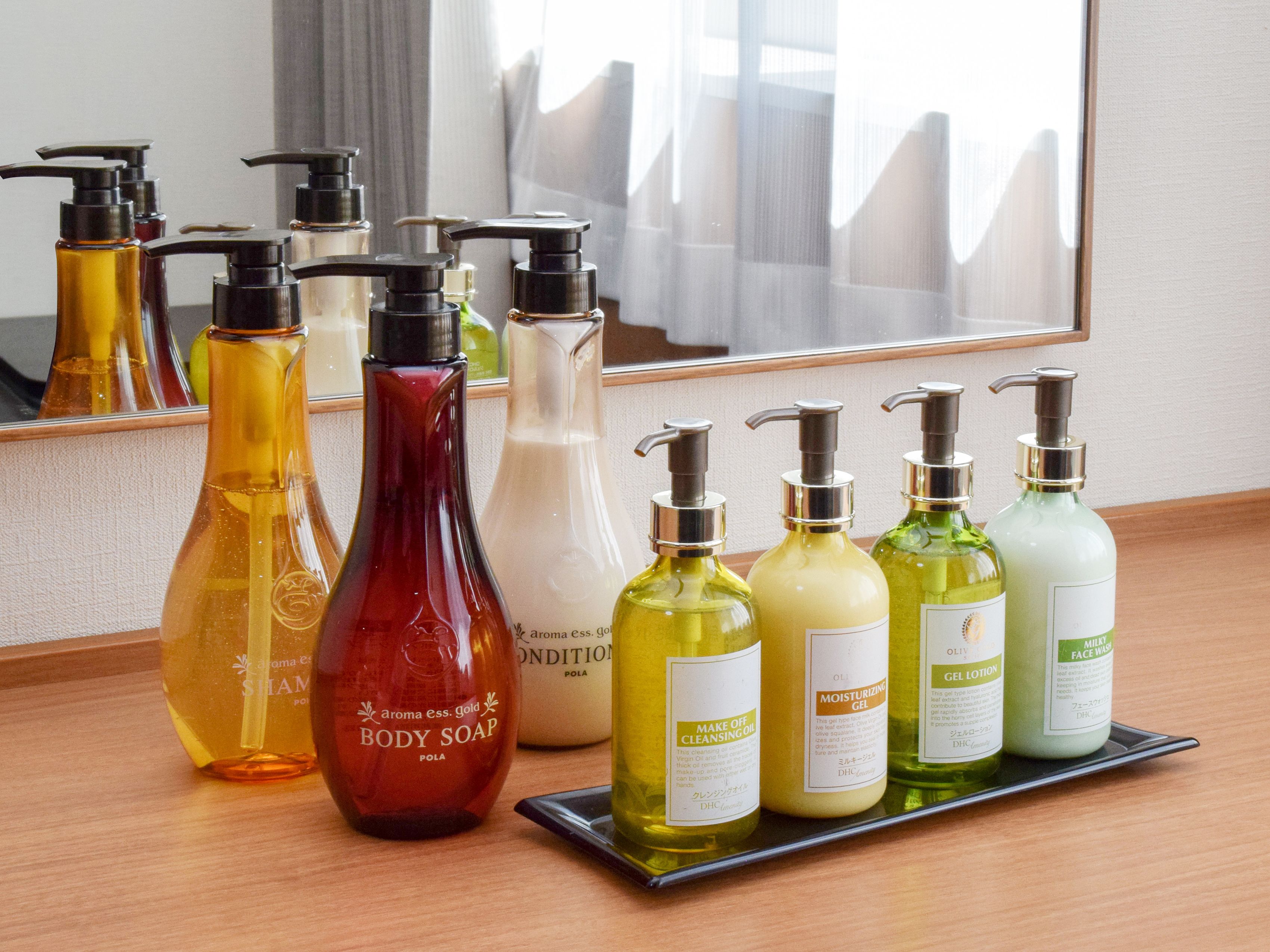 Une variété de produits de toilette disposés sur un plateau, notamment du savon pour le corps, une huile démaquillante, un gel hydratant et un nettoyant pour le visage.