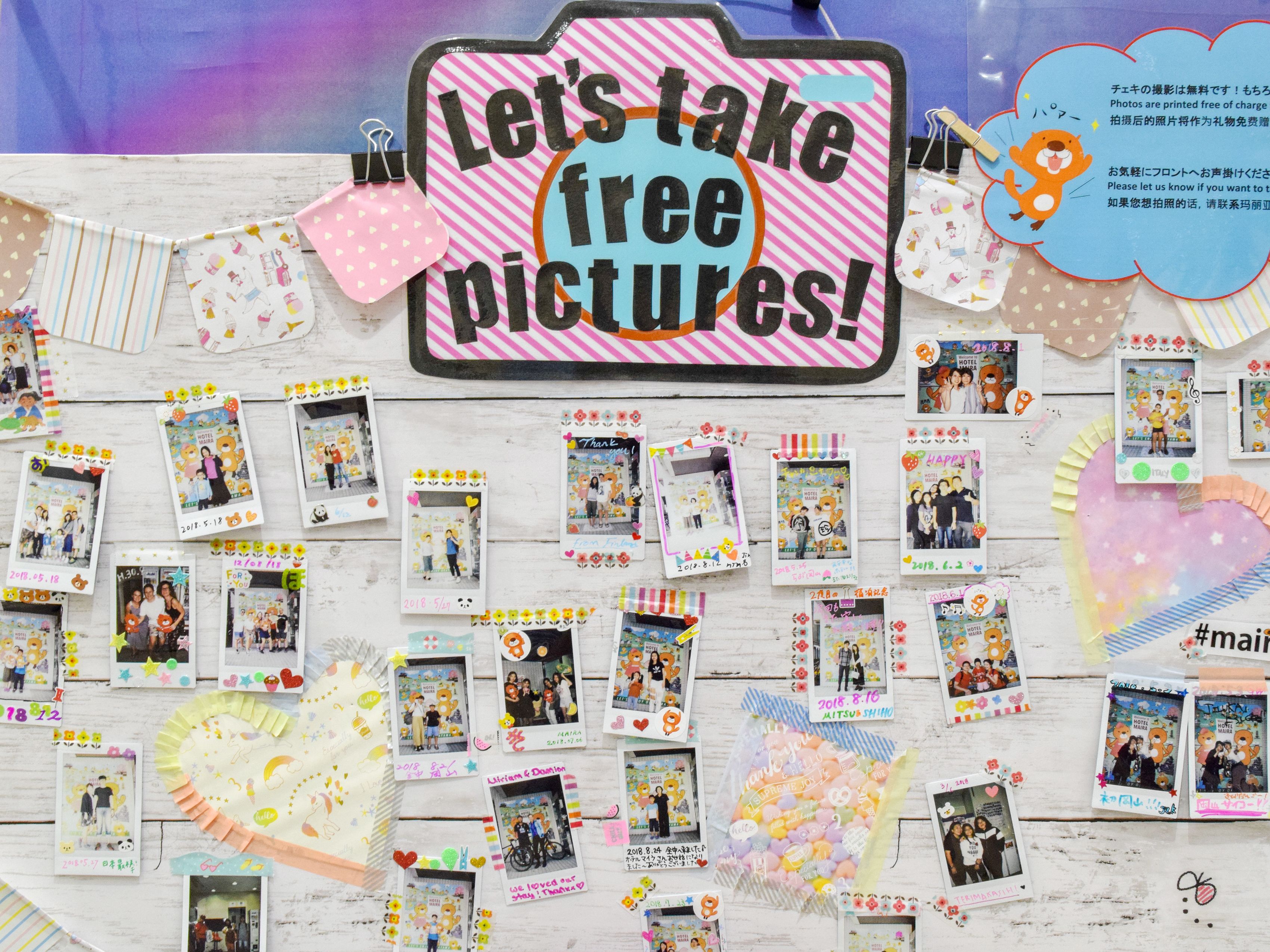 A wall decorated with numerous photos and a sign that says "Let's take free pictures!"