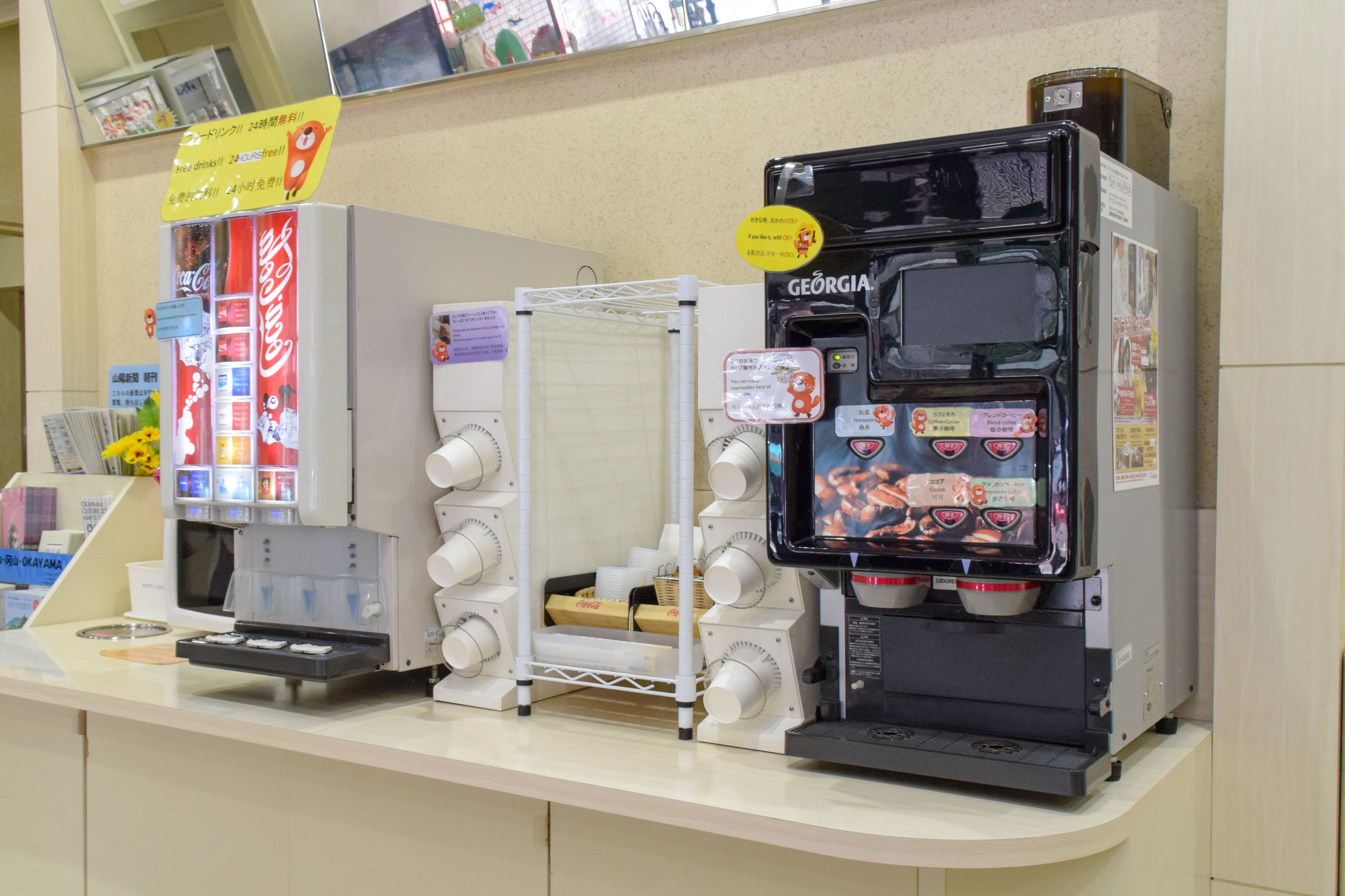A coffee machine with a digital display and a Coca-Cola refrigerator.