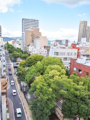 Une vue urbaine comprenant une rivière, des bâtiments et une route avec des véhicules.