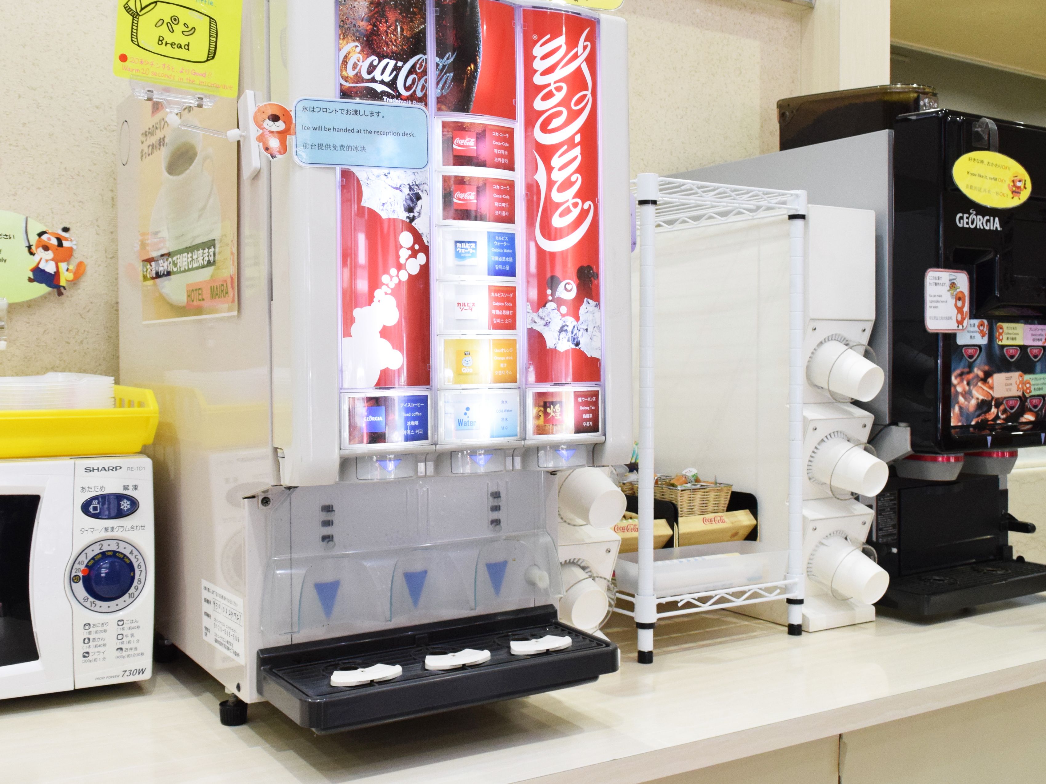 A vending machine area with a Coca-Cola machine, a water dispenser, and a coffee machine.
