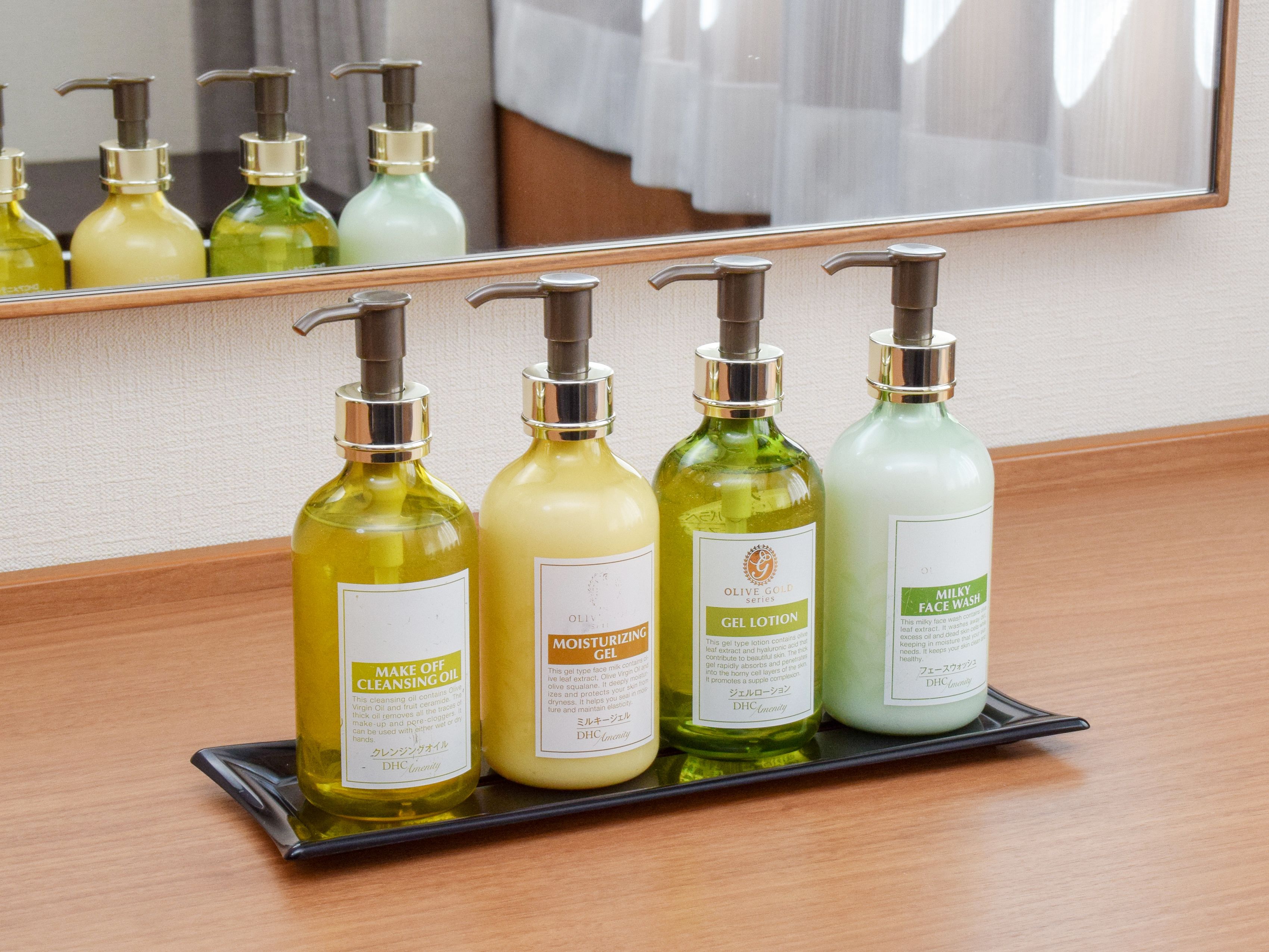 A tray with four bottles of skincare products on a wooden surface.