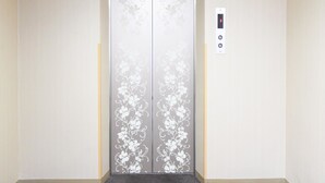 Een lift met bloemenpatronen op de deuren en een bedieningspaneel met knoppen.