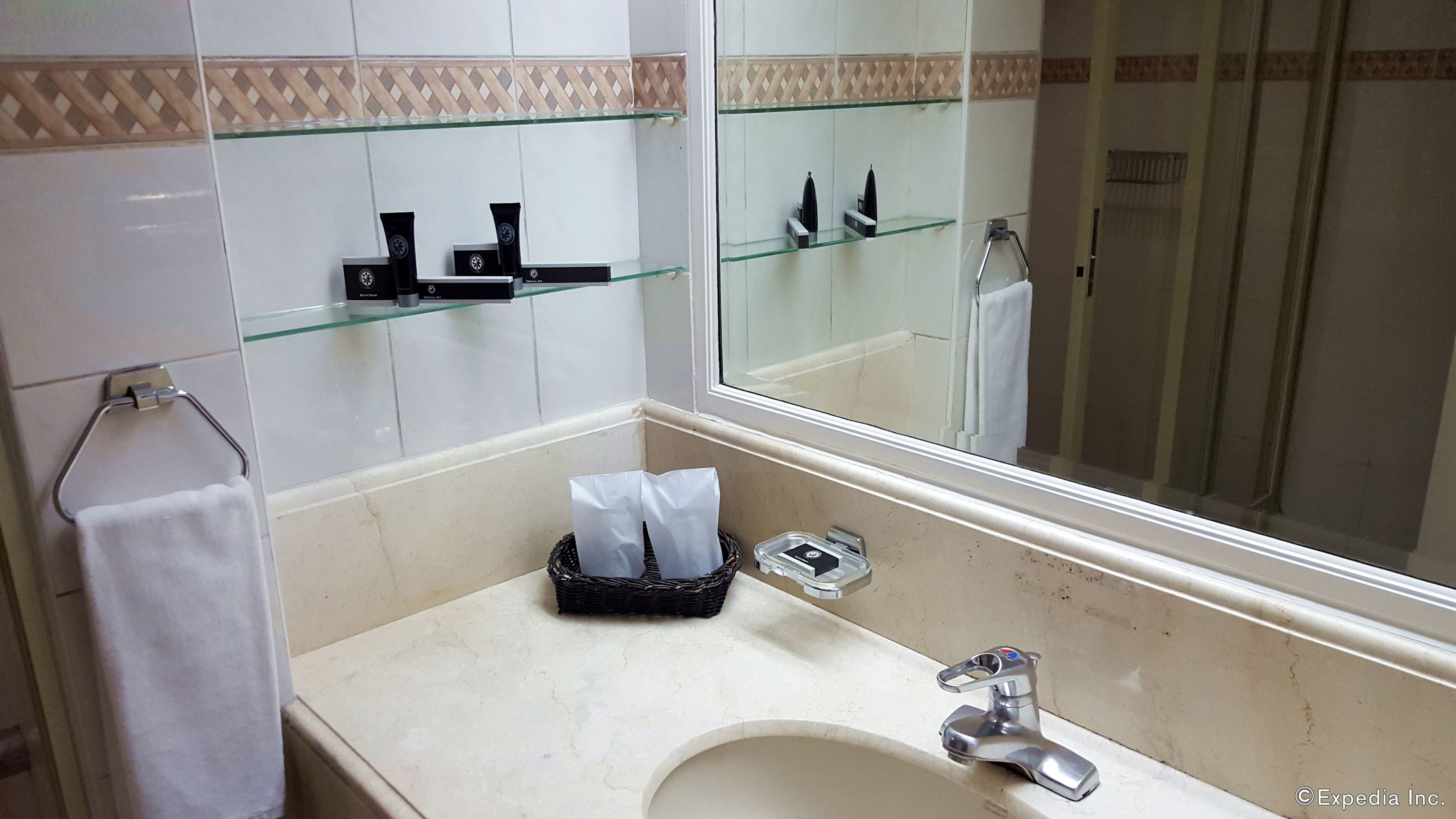 A bathroom with a sink, mirror, and glass shelves.