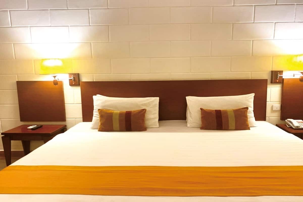 Habitación de hotel con una cama grande, dos mesitas de noche, un teléfono y dos lámparas de pared.