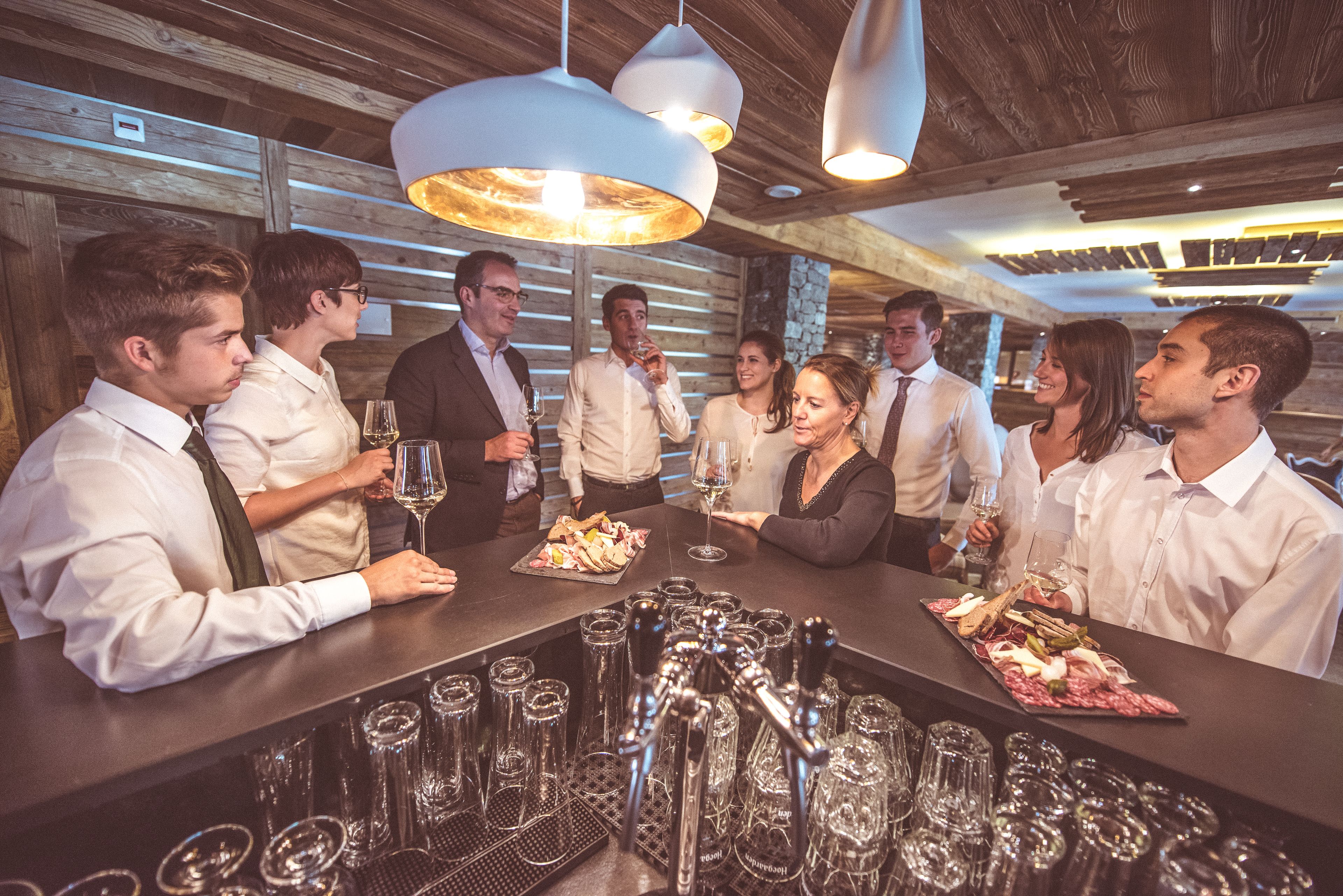 A bar area with a long counter, multiple wine glasses, and a variety of bottles.