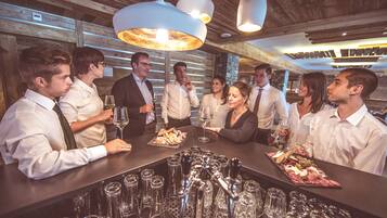 A bar area with a long counter, multiple wine glasses, and a variety of bottles.