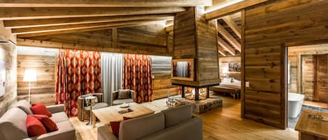 A cozy log cabin interior with a living area featuring sofas, a coffee table, and a fireplace.