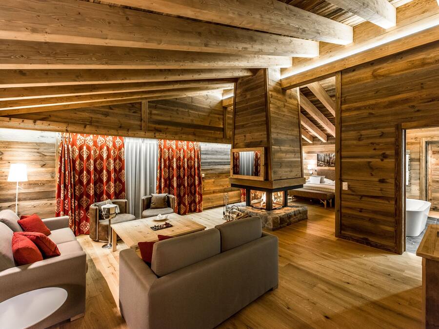 Accogliente interno di una baita in legno, con un soggiorno dotato di divani, un tavolino da caffè e un camino.