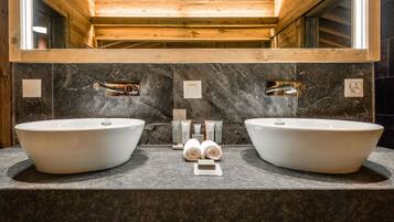 A bathroom with two large white sinks, a mirror above, and a wooden ceiling.