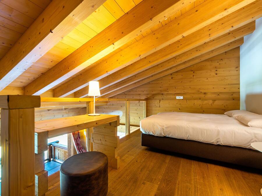 A wooden interior with a bed, a table, and a bench.
