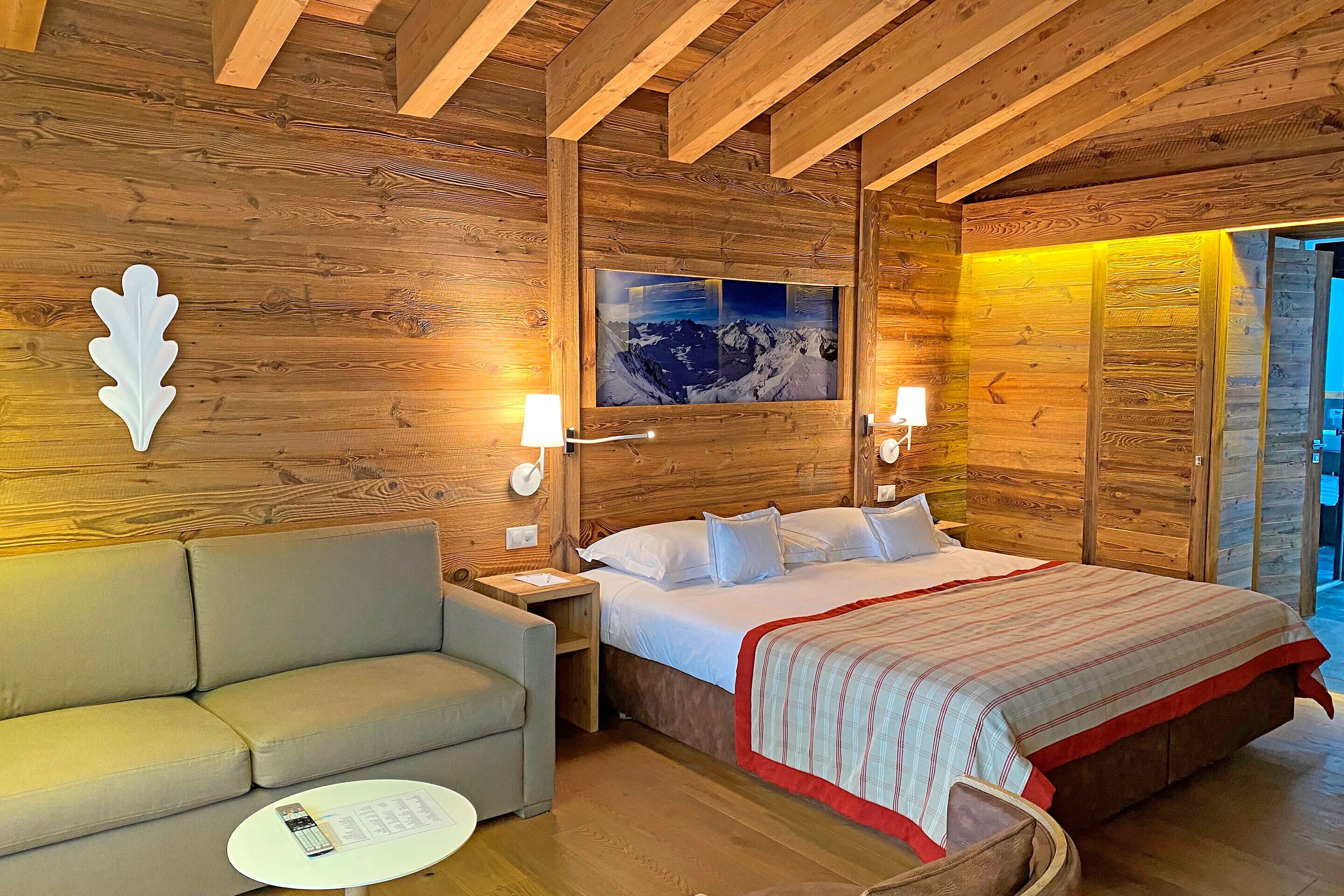 A cozy wooden room with a bed, a sofa, and a small table.