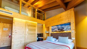 A wooden cabin bedroom with a bed, a painting, and a small bathroom.