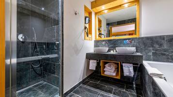 A modern bathroom with a glass-enclosed shower, a vanity with two sinks, and a bathtub.