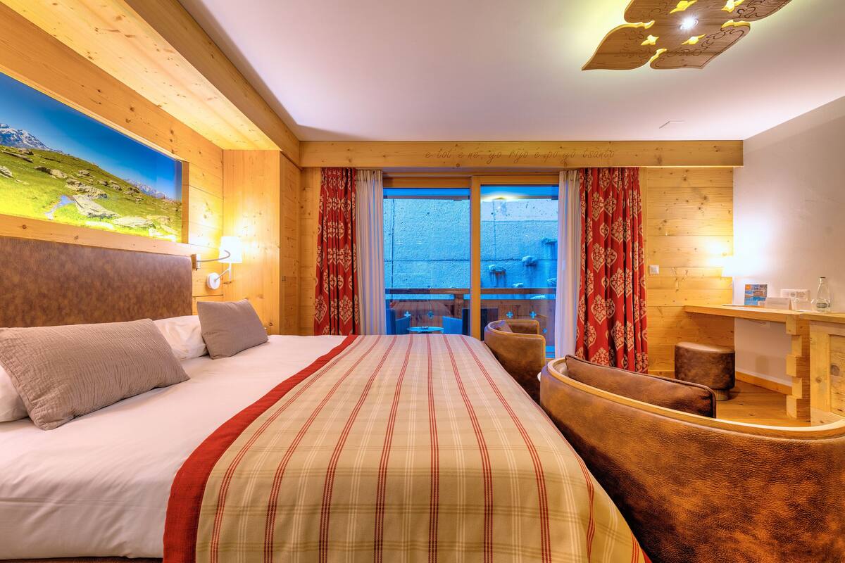 Habitación de hotel con cama, una silla, escritorio y vistas al exterior.
